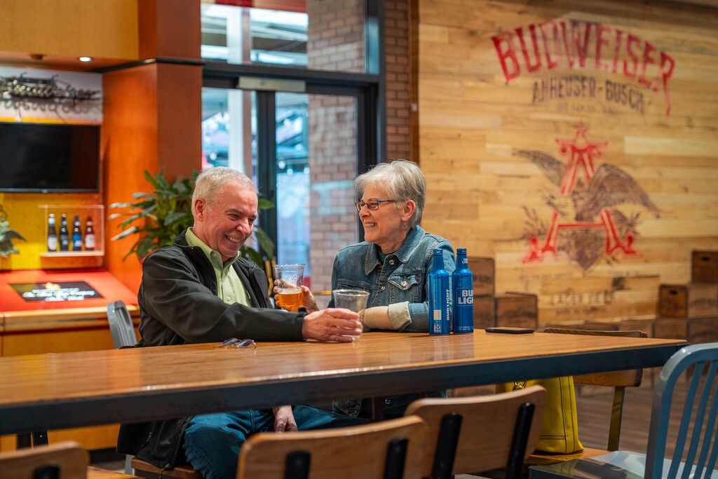 Couple sits at bar table and enjoys drinks at a brewery.