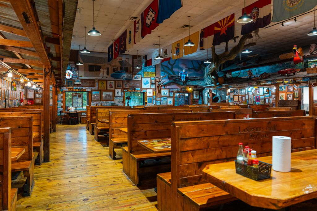 Framed photos, drawings and historical items line the walls of a rustic restaurant. Booths made of wood planks fill the room.