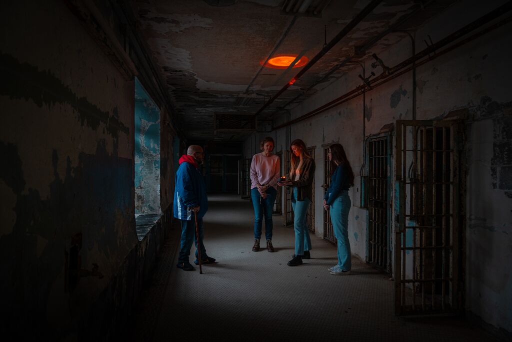 Four people stand in a corridor lit from the light of a ghost hunting tool at the history Missouri State Penitentiary in Jefferson City.