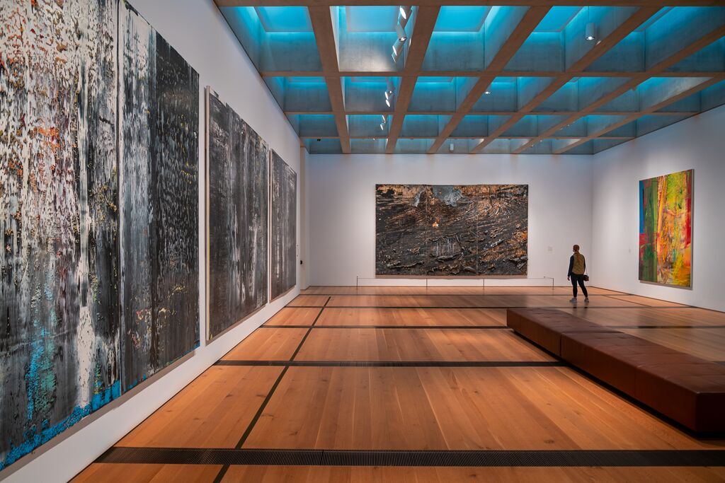 A person looks at a three panel art installment.