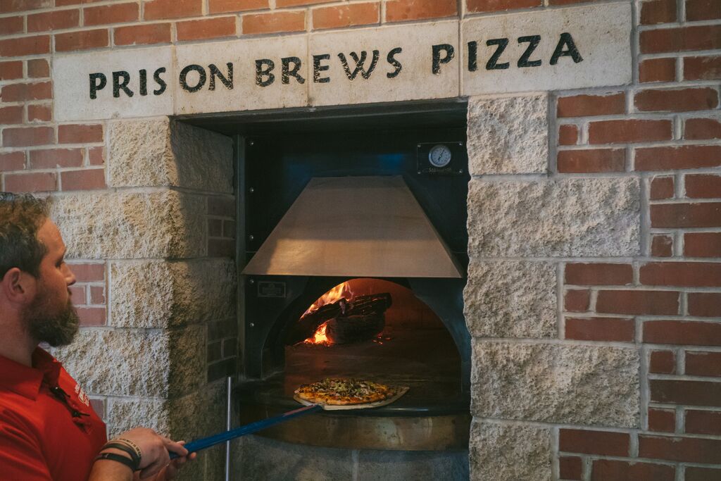 A man bakes a pizza in a wood-fired oven at Prison Brews restaurant in Jefferson City.